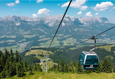 Blick aus einer Gondel der Brandstadlbahn auf das Bergmassiv des Wilden Kaisers und das grüne Tal.