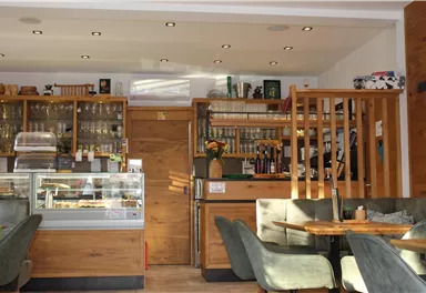 Ein gemütliches Café mit Holzregalen und einer VerkaufsTheke. Die Einrichtung ist modern und einladend.