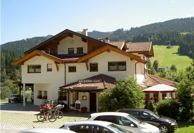 A cozy café with a charming alpine design. In the background, green meadows and forests can be seen.