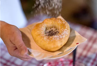 A freshly baked pastry is sprinkled with powdered sugar and a filling. It is placed on a plate while someone holds it.
