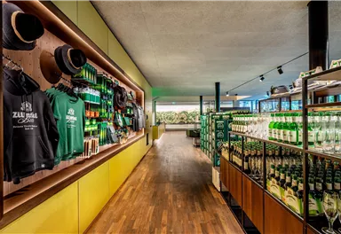A modern-designed sales area with shelves full of drinks and merchandise items. The walls are colorfully decorated, and the wooden floors create an inviting atmosphere.