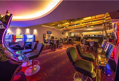 A modern casino with colorful slot machines and elegant seating areas. The atmosphere is inviting and lively.