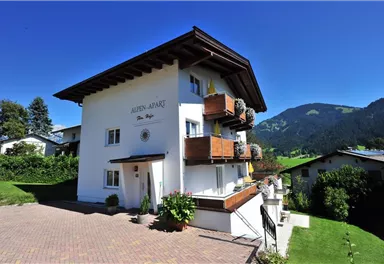 A charming holiday home with balconies and blooming plants. It is located in a picturesque mountain landscape.