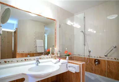 A modern bathroom with a bathtub and a shower. The walls are tiled in light colors, and the sink is elegantly designed.