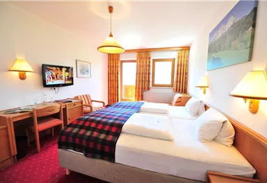 A bright hotel room with two single beds, a television, and a desk.
Large windows let in plenty of daylight and offer a view of the surroundings.