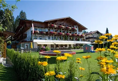 A picturesque café with a beautiful garden and colorful flowers. The building is surrounded by trees and exudes an inviting atmosphere.