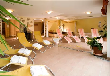 A relaxing wellness area with loungers and plants. The atmosphere is calm and inviting.
