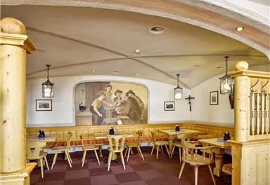 Ein gemütliches Restaurant mit Holzmöbeln und einem lebendigen Wandgemälde. Die Atmosphäre ist einladend und traditionell.