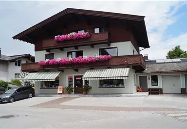 A charming, traditional building with flower boxes and terraces. The surrounding area is quiet and inviting.