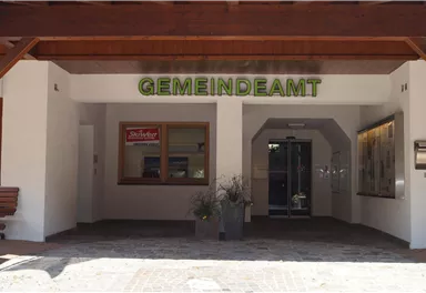 A community office with an inviting entrance. Above the door, "GEMEINDEAMT" is written in green letters.