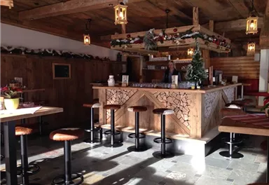 Eine gemütliche Bar mit Holzdekor und hohen Stühlen. Die Einrichtung ist rustikal und festlich geschmückt.