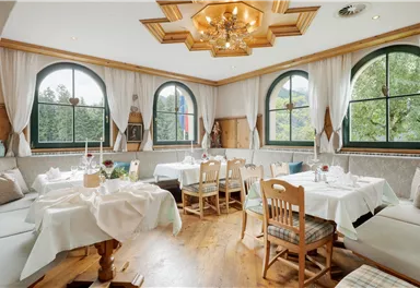 A cozy restaurant with large windows and elegant decor. The tables are set festively and the atmosphere is inviting.