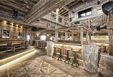 Eine rustikale Innenansicht eines gemütlichen Restaurants mit Holzdekor. Die Atmosphäre ist einladend und modern, mit Beleuchtung und bequemen Sitzbereichen.