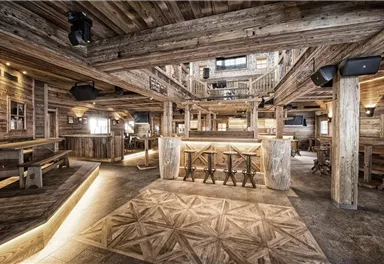 Ein stilvolles Restaurant mit rustikalem Holzinterieur und gemütlicher Atmosphäre. Die Bar ist zentral platziert und von gemütlichen Sitzbereichen umgeben.