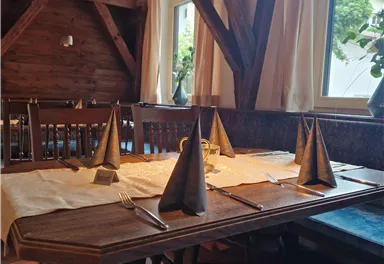 Ein gemütliches Restaurant mit Holzmöbeln und einem offenen Kamin. Die warmen Farben und die liebevolle Dekoration schaffen eine einladende Atmosphäre.