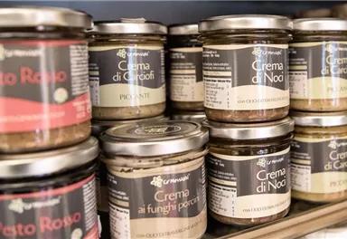 A variety of jars with different spreads on a shelf. The products include pesto, mushroom cream, and artichoke cream.