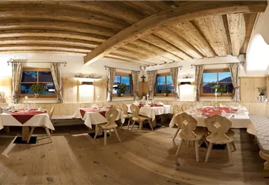 A cozy restaurant with wooden furniture and traditional decor. The tables are elegantly set, creating an inviting atmosphere.