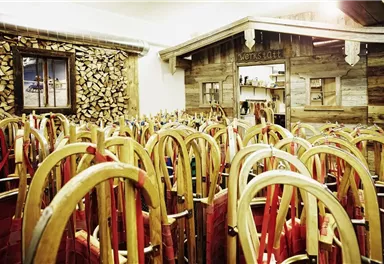 Ein gemütlicher Raum mit vielen Holzskiern und einer rustikalen Holzdeko. Im Hintergrund befindet sich eine kleine Holzhütte.