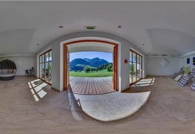 A stylish room with large windows that offer a view of the mountains. The room features comfortable loungers and a cozy seating area.