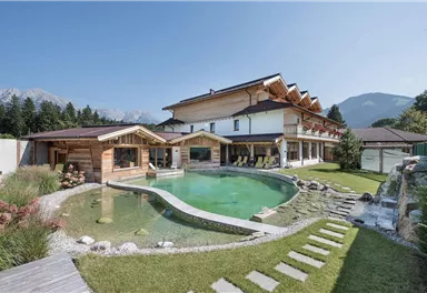 Ein modernes Haus mit traditionellem Holzdesign und einem schönen Garten. Der Garten hat einen Schwimmteich und eine malerische Landschaft im Hintergrund.
