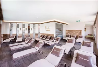 Ein moderner Wellnessbereich mit komfortablen Liegen. Die große Fensterfront sorgt für viel Tageslicht und eine entspannende Atmosphäre.