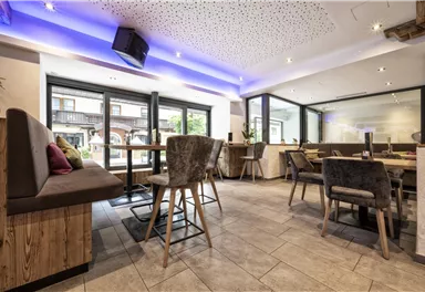 Ein modernes Restaurant mit elegantem Interieur und hellem Licht. Das Design ist einladend mit bequemen Sitzgelegenheiten und großen Fenstern.