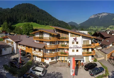 Ein gemütliches Hotel inmitten von grünen Hügeln und Bergen. Der klare Himmel und die einladende Atmosphäre schaffen ein perfektes Urlaubsziel.