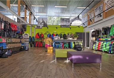 Ein moderner Sportladen mit einer großen Auswahl an bunten Outdoor-Bekleidungen. Die Einrichtung ist hell und einladend, mit einem offenen Raum und einem gemütlichen Sitzbereich.