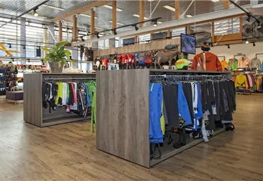 Ein bekannter Sportladen mit Kleidung an Kleiderständern und einer hellen, einladenden Atmosphäre. Die Regale sind ordentlich und gut organisiert.