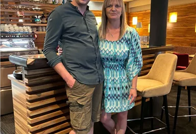 A man and a woman are standing in a modern restaurant. The decor is bright and inviting.