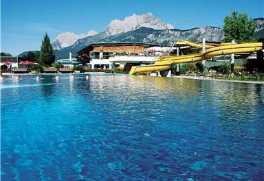 Ein glitzernder Pool mit einem gelben Wasserrutschen und einer schönen Berglandschaft im Hintergrund. Ein entspannender Ort, ideal für einen Tag am Wasser.