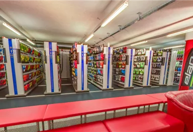 A sales area with shelves displaying various products. In the center, there are red seating furniture for customers.