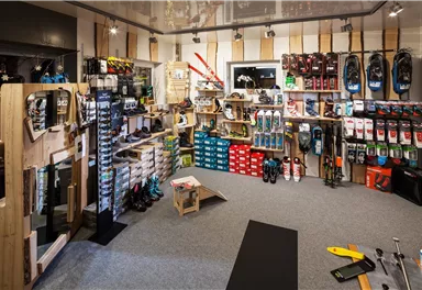 Ein Sportgeschäft mit einer großen Auswahl an Ausrüstung und Schuhen. Regale sind gefüllt mit verschiedenen Marken und Produkten.