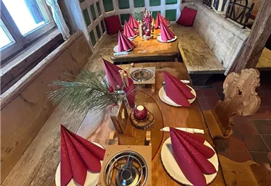 A rustic restaurant with a wooden tray that is elegantly set. Red fabric napkins and decorations create a festive atmosphere.