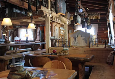 A cozy restaurant with rustic wood decor and warm lighting. The tables are neatly set, and the atmosphere is inviting.