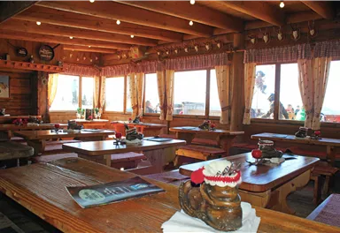 A cozy restaurant with wooden tables and benches. Large windows offer a view of the beautiful landscape.