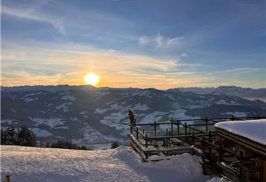 A picturesque mountain landscape in the snow with a sunset on the horizon. The view shows snow-covered mountains and a tranquil atmosphere.