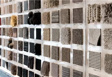 Eine Wand mit verschiedenen Stoffmustern und Texturen. Die Muster sind in verschiedenen Farben und Materialien angeordnet.