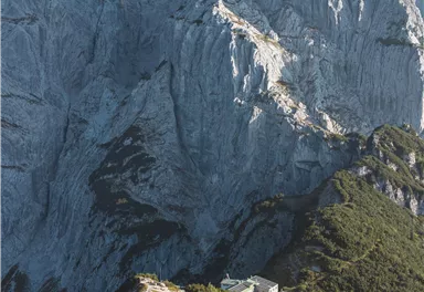 An impressive mountain landscape with steep rocks and a beautiful meadow in the foreground. In the background, the rock rises majestically.