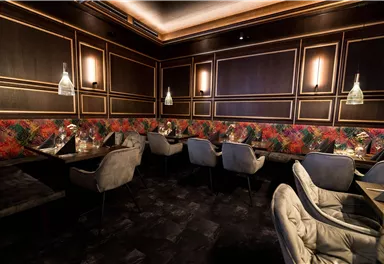 Ein elegantes Restaurant mit stilvollen Sitzplätzen und einem warmen, einladenden Ambiente. Die Wände sind mit bunten Mustern gestaltet und die Beleuchtung ist sanft.
