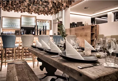 An elegant restaurant with a modern decor. The table is festively set with glasses and napkins.