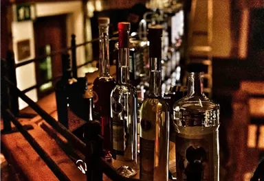 A stylish bar with a variety of bottles. The light creates a cozy atmosphere.