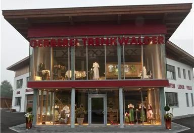Ein modernes Geschäft mit großen Fenstern und stilvoller Bekleidung. Die Fassade ist rot und hat ansprechende Dekorationen.