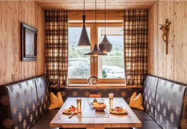 A cozy dining area with wooden paneling and a large table. On the table are small plates with food and two glasses of beer.