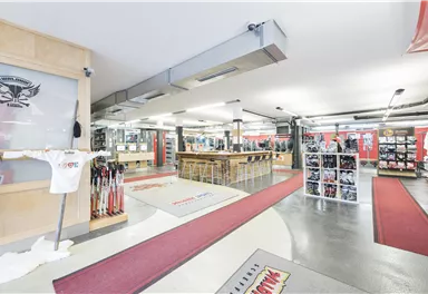 A large athletic sales room with shelves full of equipment. In the center is a long counter with space for customers.