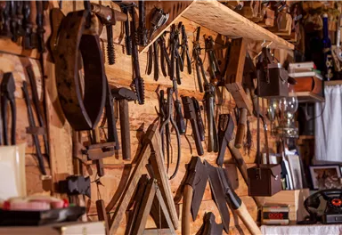 Eine Wand voller handwerklicher Werkzeuge in einer Holzwerkstatt. Verschiedene Werkzeuge sind ordentlich angeordnet und zeigen ein kreatives Arbeitsumfeld.