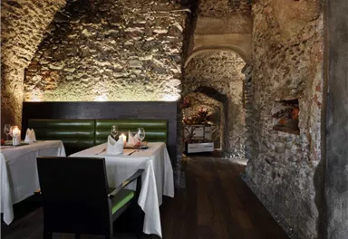 Ein stilvolles Restaurant mit rustikalem Steininterieur. Zwei gedeckte Tische stehen in einer gemütlichen Atmosphäre.