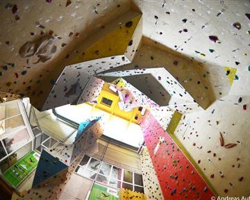 A climbing gym with colorful climbing walls and many grips. The ceiling is high and offers various routes for climbers.