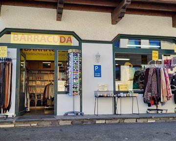Ein Geschäft mit dem Namen "Barracuda" ist zu sehen. Davor hängen verschiedene Gürtel und Bekleidungsartikel.