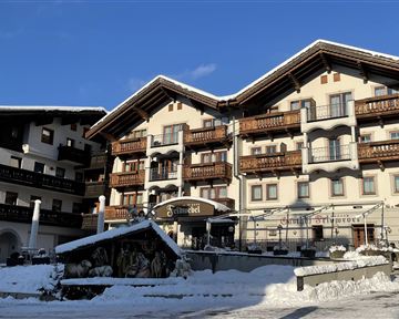 A cozy hotel in the mountains, surrounded by snow. The clear sky and alpine architecture create an inviting atmosphere.
